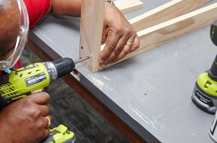 A person connecting two lengths of timber using a cordless driver