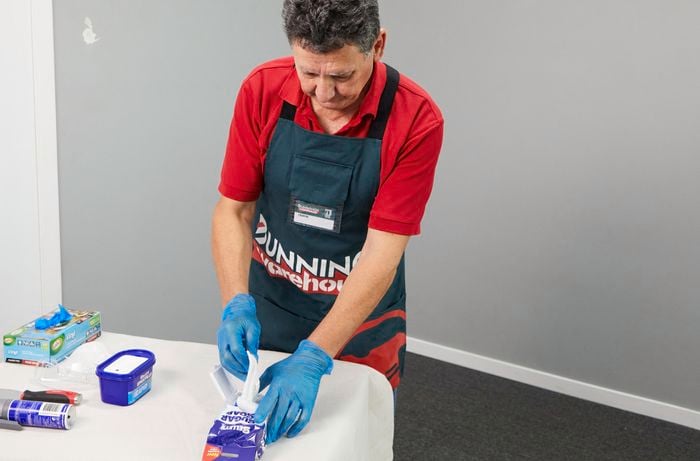 Tools and materials needed to prepare an interior wall for paint on a table.