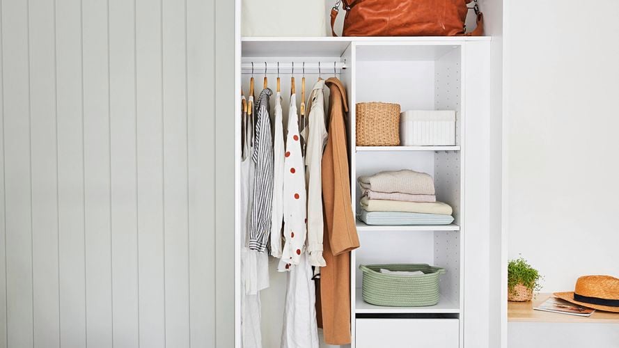A well-organised and decluttered wardrobe with storage and some hanging items.