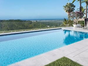 A large pool with a glass fence and a view of the landscape.