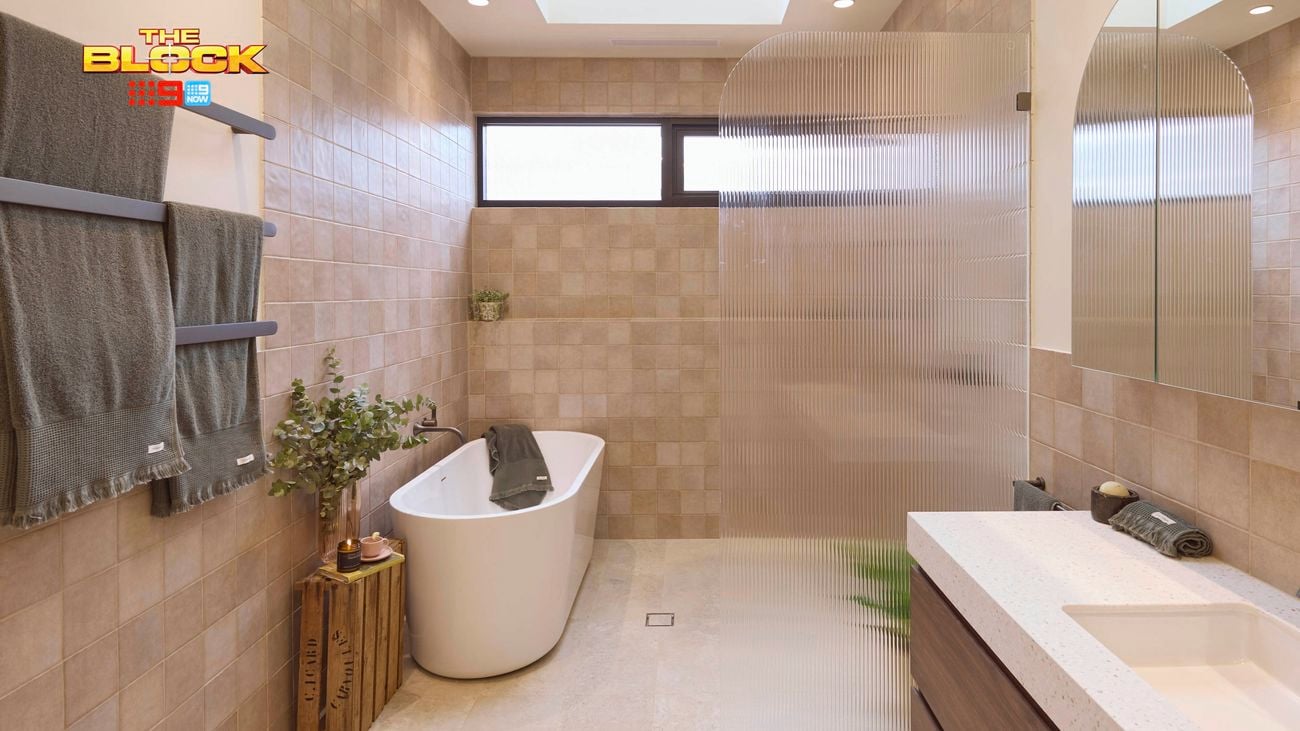Natural coloured brown bathroom with timber vanity, white marble benchtop, curved shower screen and bath
