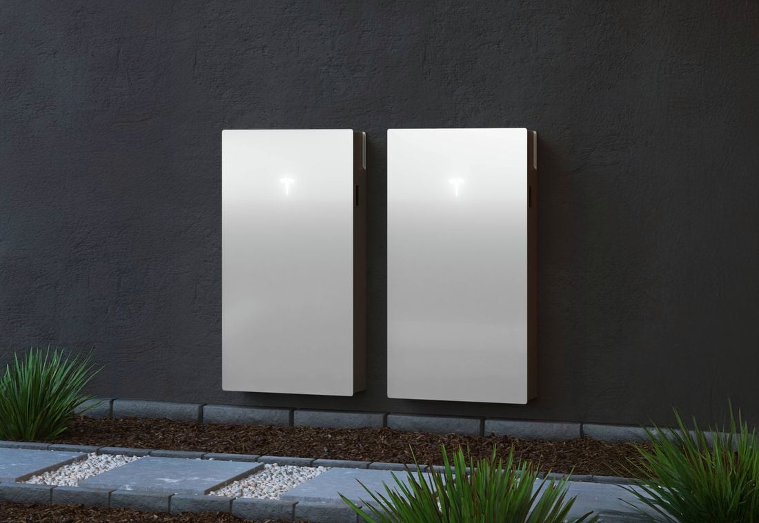Modern house with Tesla car parked in the driveway and a tesla powerwall on the side of the house
