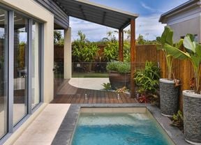 Outdoor lap pool surrounded by lush plants.