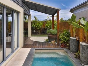 The exterior of a modern home with a covered deck and swimming pool.
