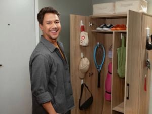 A man standing in front of a cupboard, with exercise equipment stored using Command wall hooks