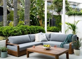 Timber and grey outdoor setting on a patio surrounded by greenery.