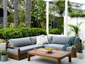 Timber and grey outdoor setting on a patio surrounded by greenery.
