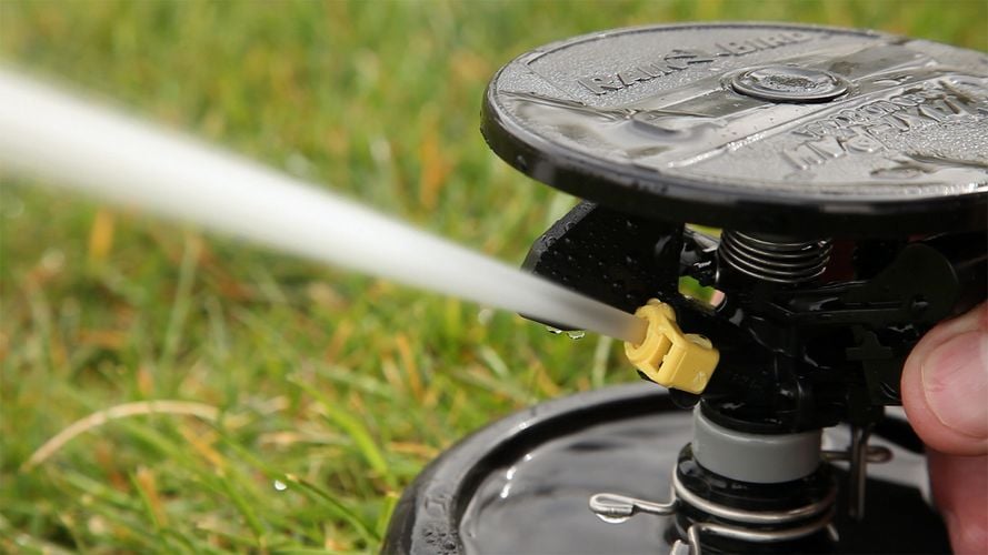 Close up of a rotating sprinkler head with water spraying out