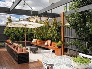 Outdoor lounge with four white chairs, a table and a BBQ next to it.
