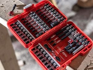 An open case containing a full set of power drill bits sitting on a length of wood