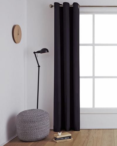 Interior of a modern living room with a timber floor and dark coloured curtains on a metal curtain rod over the window