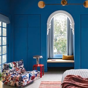 Bedroom painted in blue with a red table lamp in frame