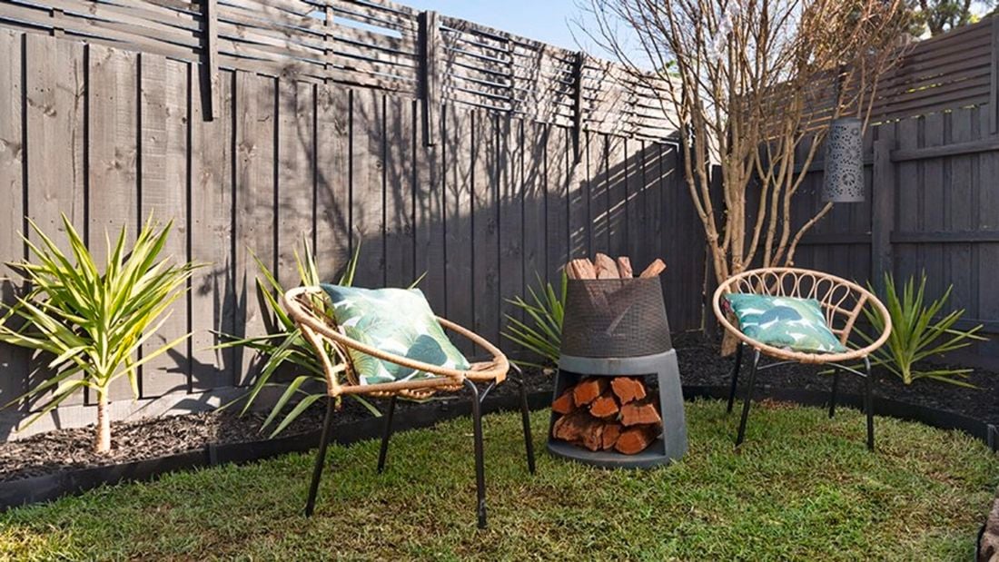 An outdoor sitting area around a wood brazier, with fence extensions installed on top of a wooden fence