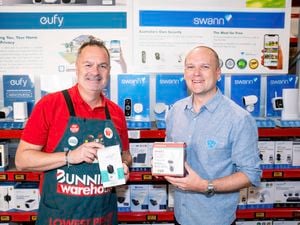 Bunnings team member wearing an apron in store standing next to a representative holding home security products.