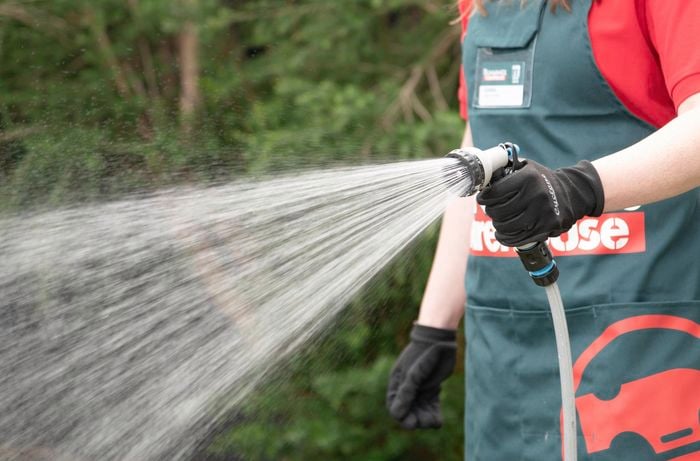 A person watering a lawn with a sprayer hose