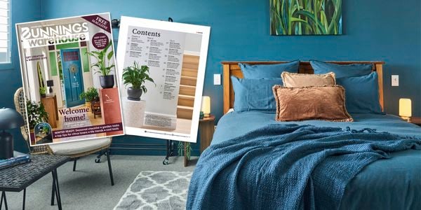 Styled bedroom with teal walls, wooden bed, and cushions, alongside Bunnings Warehouse Winter 2026 magazine cover and contents page displayed on a chair.