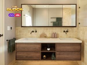 Modern bathroom with double sink vanity, large mirror, light tiles, glass shower partition, and white door with black hardware. 