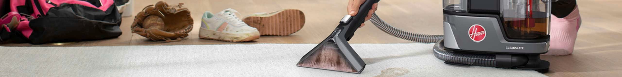 A women cleaning a rug with a Hoover cordless.
