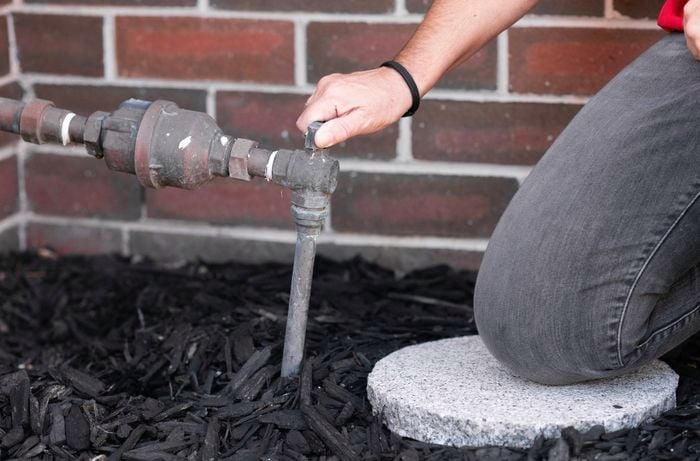 A person is turning off the water supply.