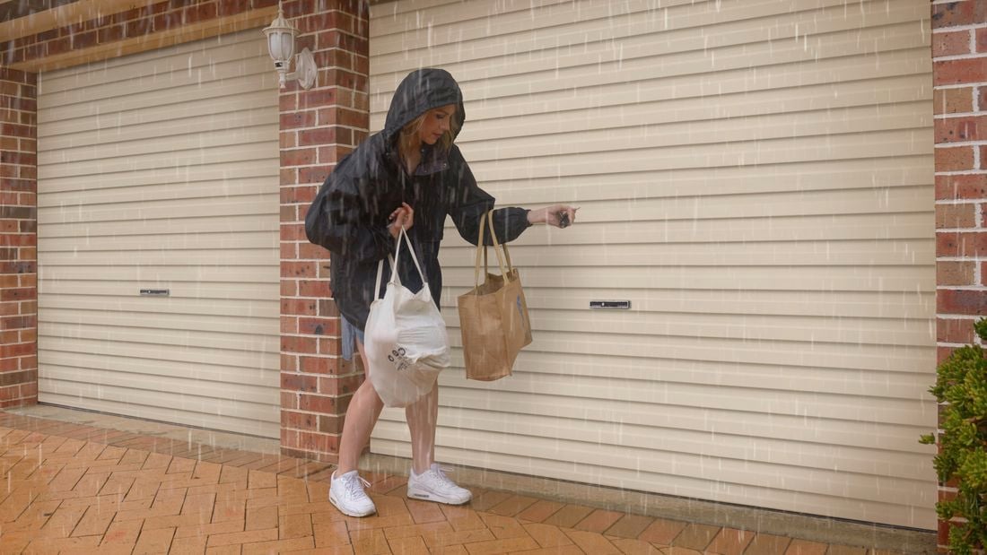 A woman in the rain opening a garage door