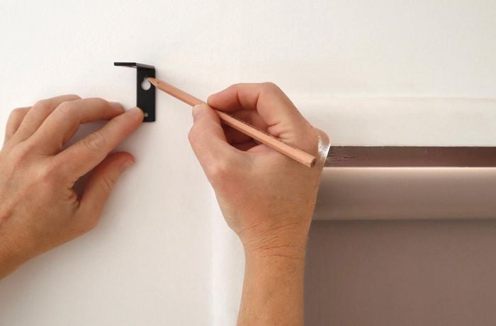 A pair of hands marking the drill holes on a wall