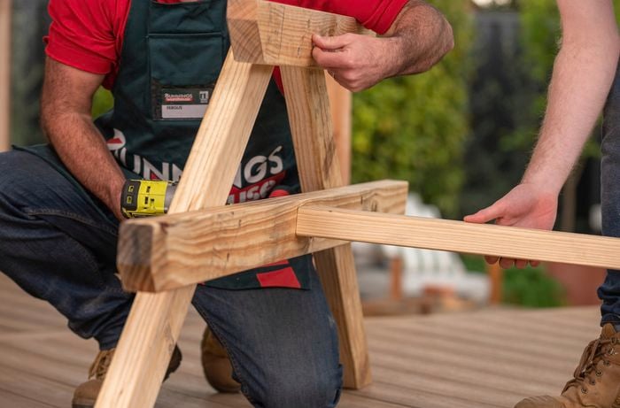 Assembling cross rail on the picnic bench using a drill