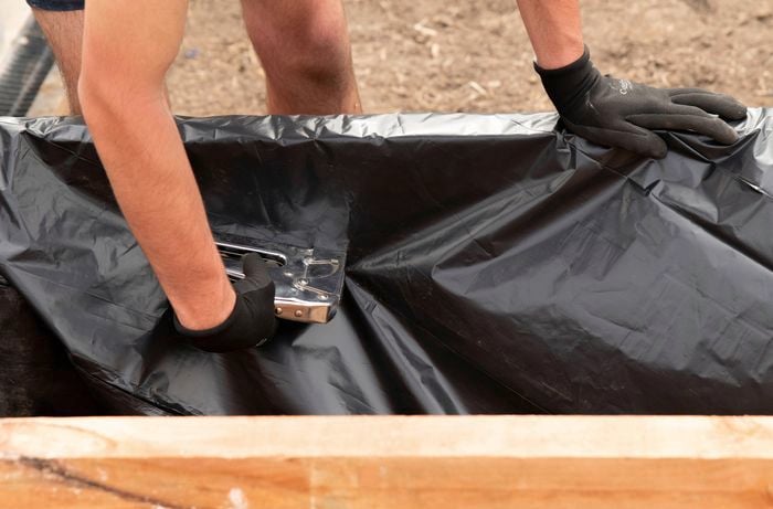  Line a raised garden bed with a protective barrier 