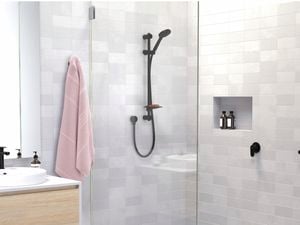 A walk-in shower with grey and white tiles and a glass screen