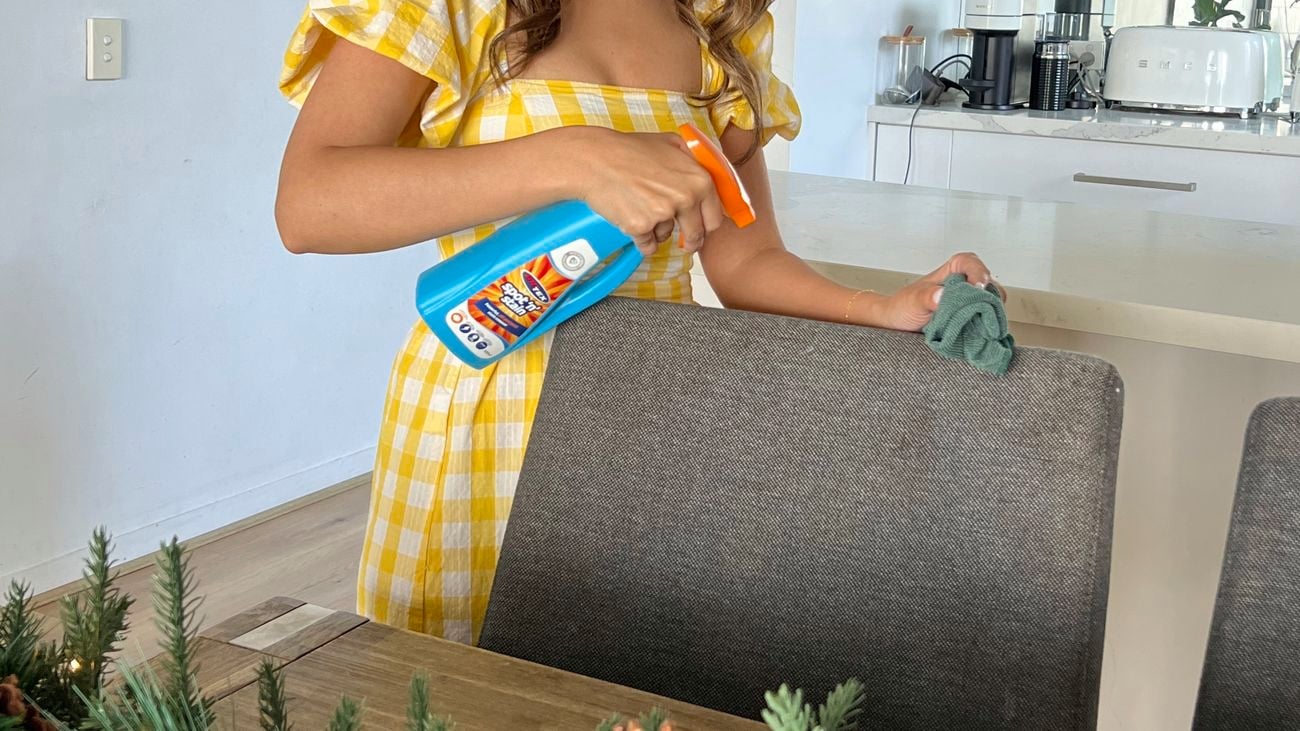 Woman uses Britex spray bottle to clean fabric chairs