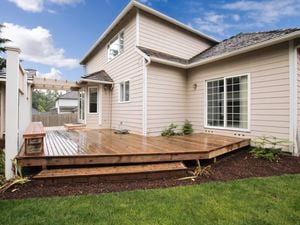 Two-storey weatherboard house with outdoor deck and garden