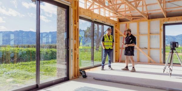 Two people standing inside a house that is in construction