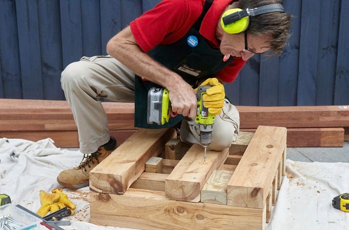 Framework for one end of a wooden outdoor day bed being screwed together