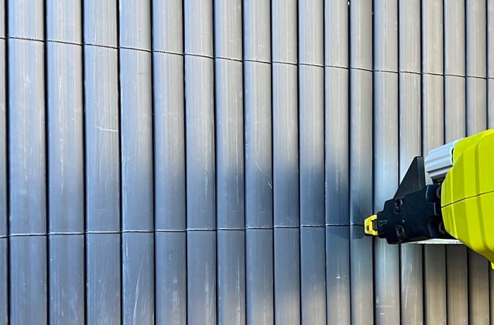 Close up image of Black cords on fence being secured by a crown stapler