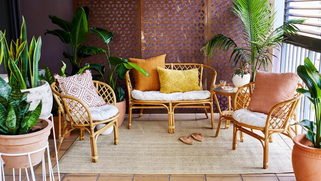 Cane chairs and potted plants in a balcony garden.
