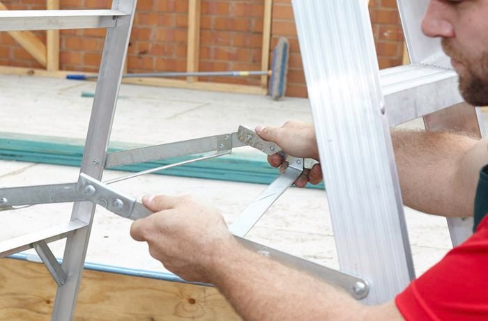 A person locking the horizontal arms on a ladder