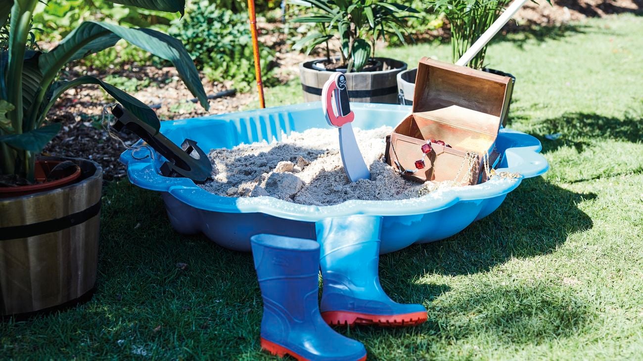Clam shell sandpit filled with kids toys.