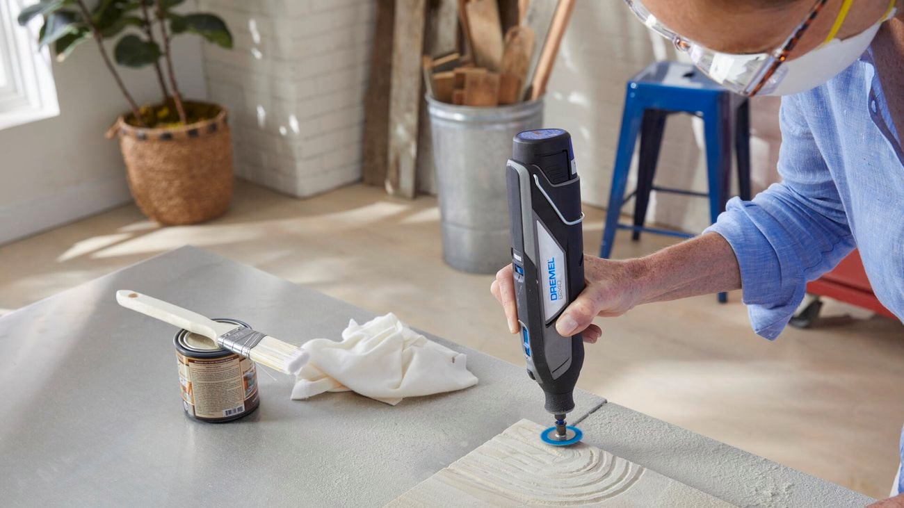 Person using Dremel sanding tool to create shapes in sandstone