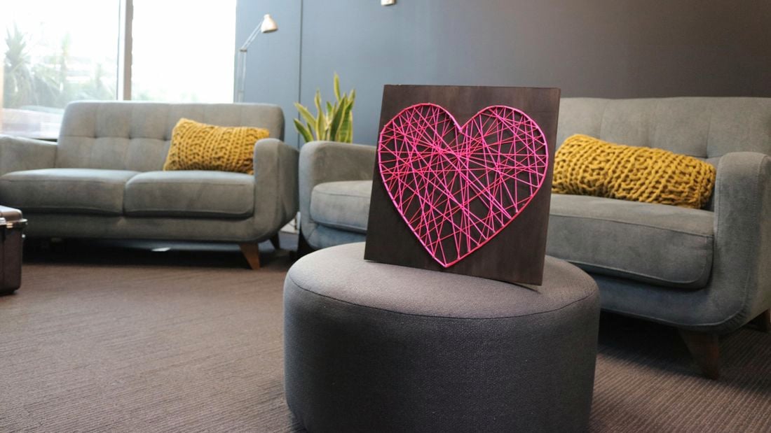 String art heart picture on an ottoman in a living room