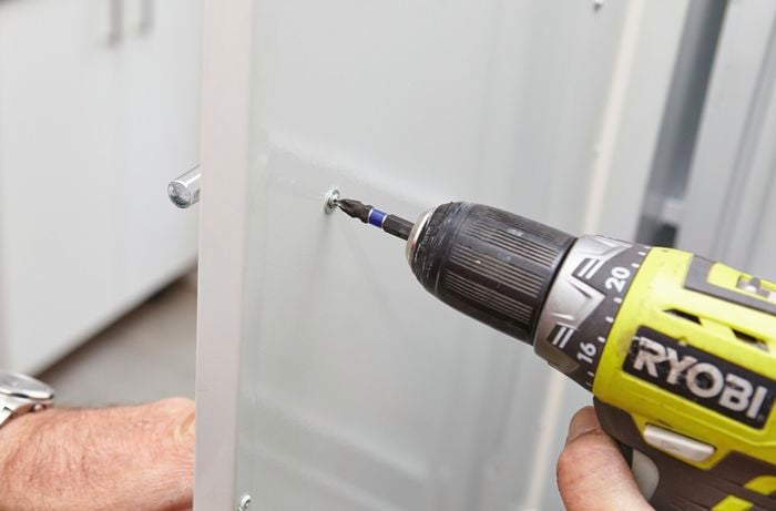 Using the drill to tighten the screws and secure the handle.