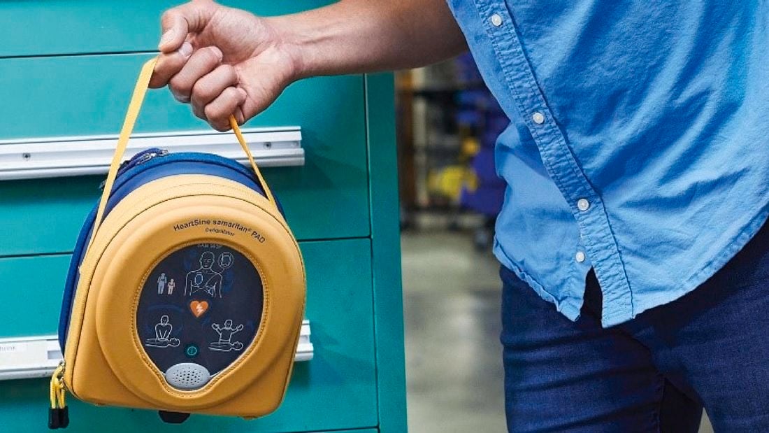 Man holding a HeartSine defibrillator.