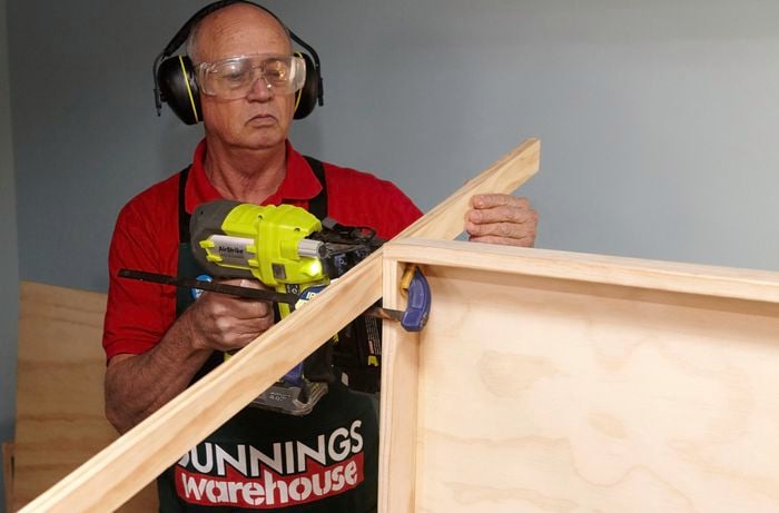 A person joining pieces of timber using a nail gun