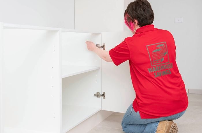 A Bunnings Team Member is attaching the door to the cabinet by connecting it to the hinge arm.