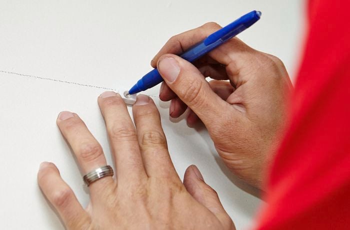 Positions of brackets being marked on a wall with a ballpoint pen by a Binnings team member