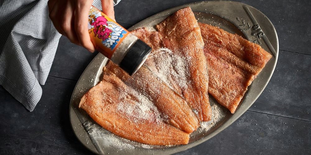 A person seasoning some pork rind.