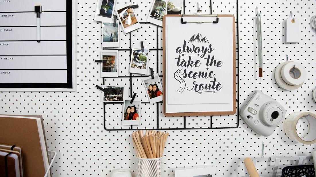 Wire mesh memo board hanging on pegboard wall, with lots of photos on it.