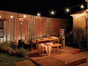 Danced outdoor entertaining area with wooden deck, wooden bench and seats, and outdoor gas heater.