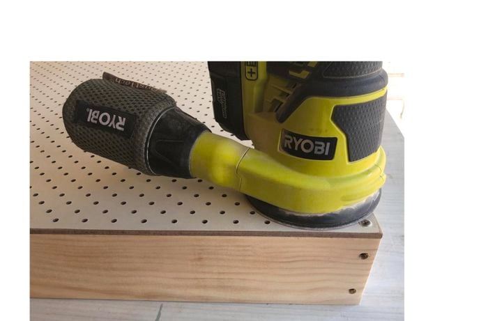 Person sanding pegboard feature piece.