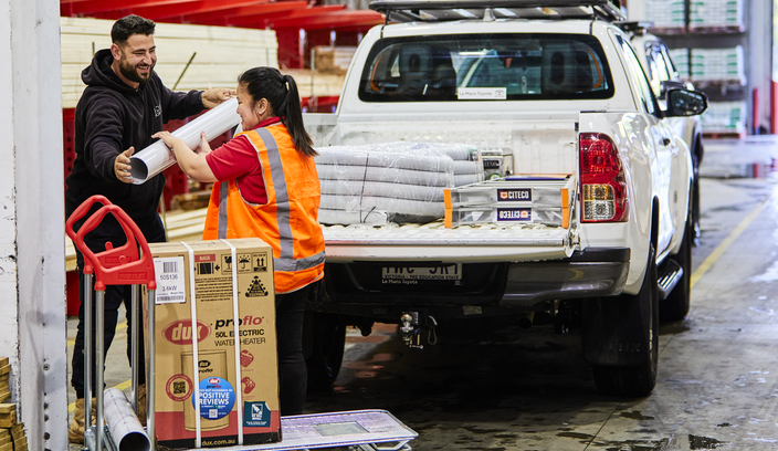 Team Member helping customer load PVC pipe into back of a ute in the timber yard