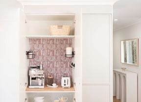 A picture of a white appliance cupboard with decorative adhesive tiles on one of the shelves in the room