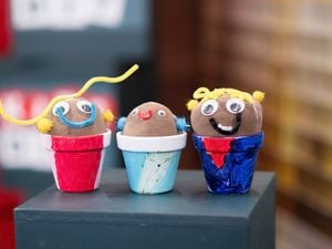 Three coloured Kids craft grass heads in pots.